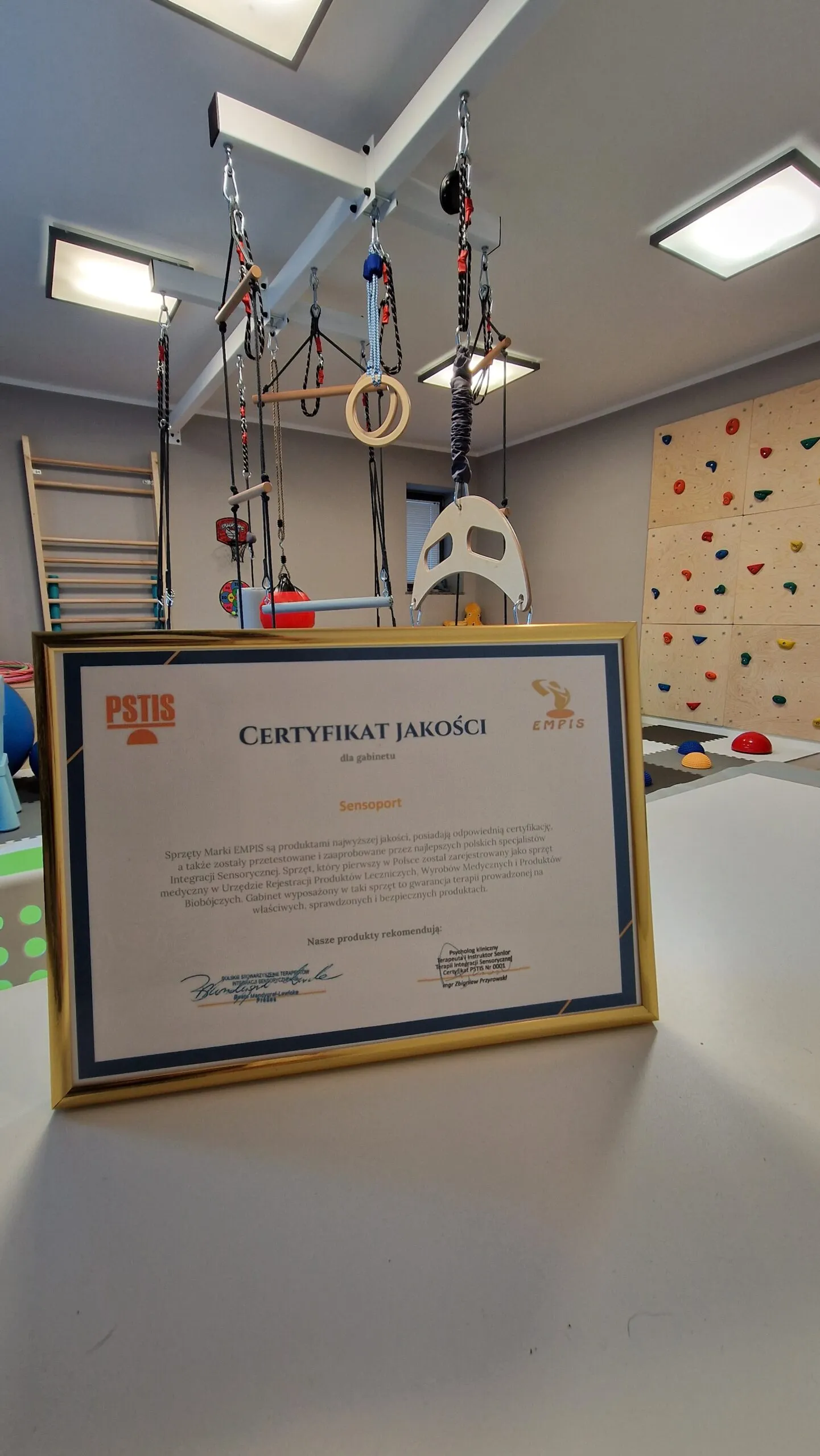 Oprawiony certyfikat jakości PSTIS na stole w sali integracji sensorycznej